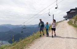 Gemeindealpe Mitterbach im Sommer. Familie wandert von der Bergstation hinunter. Im Hintergrund sieht man die Sesselbahn und den Erlaufsee.