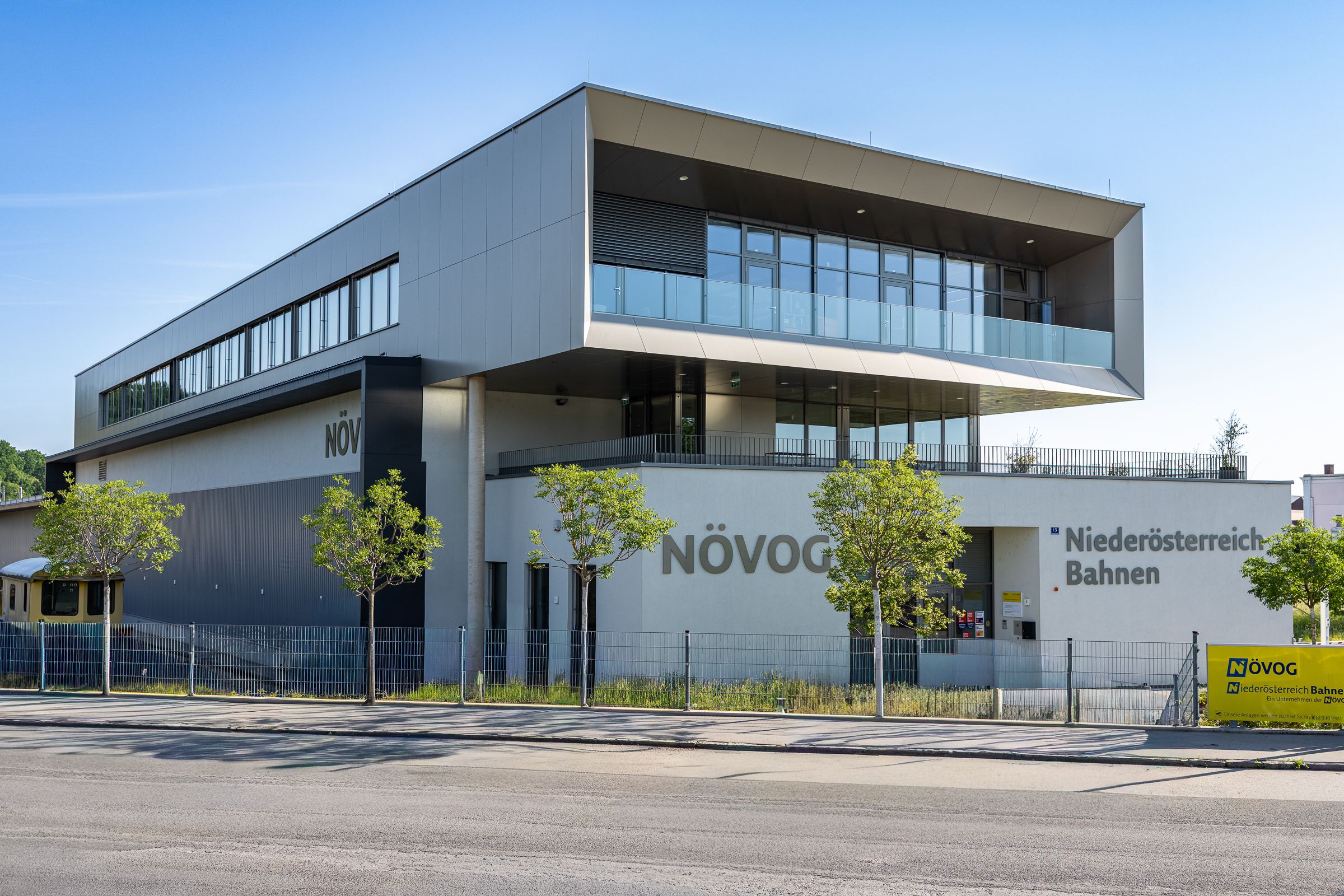 Modernes, mehrstöckiges Gebäude mit großen Fenstern und der Aufschrift 'NÖVOG Niederösterreich Bahnen' an der Fassade